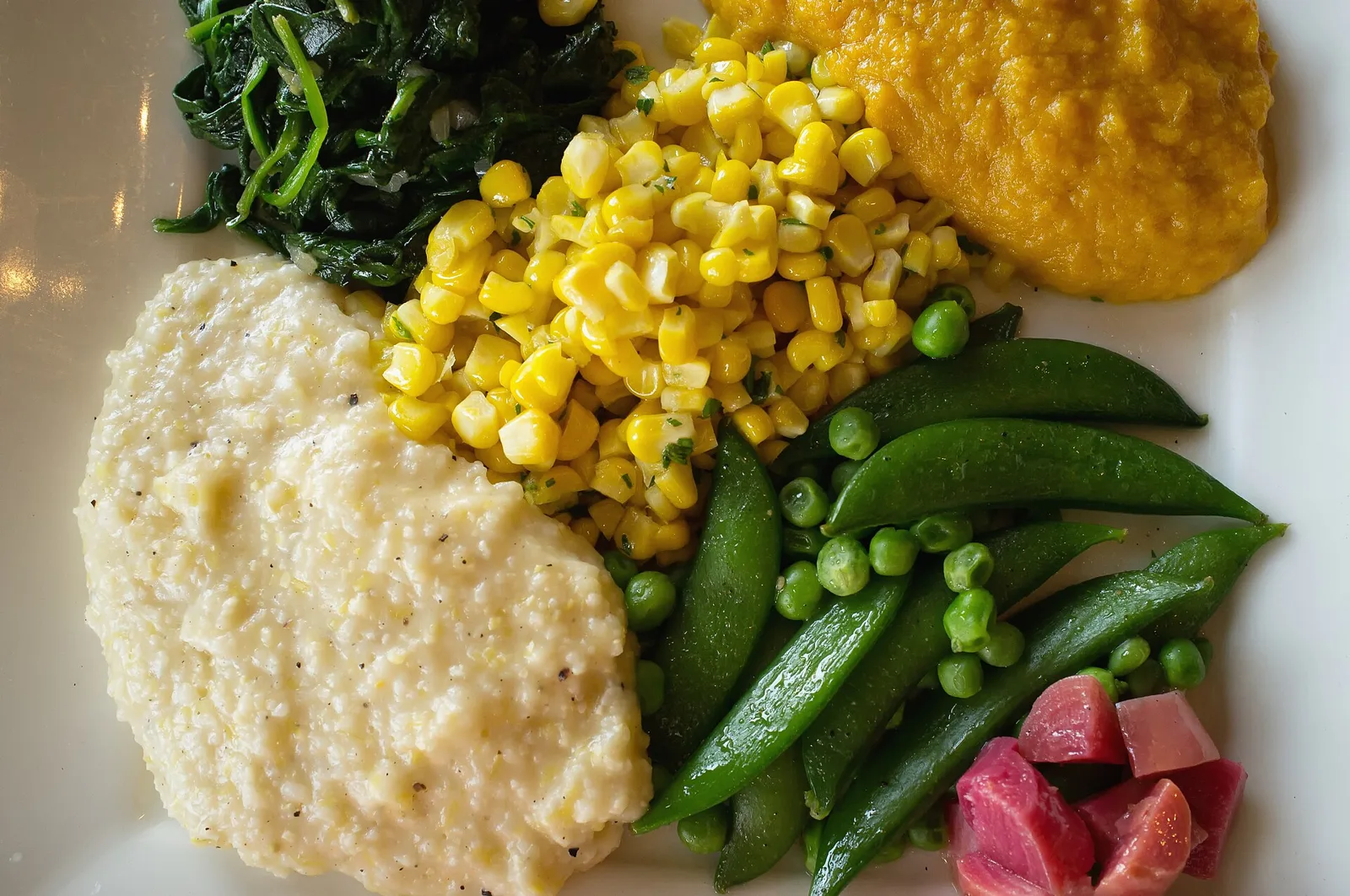A Southern vegetable plate of sugar snap peas, sweet potatoes, corn, cheese grits and spinach at a restaurant in Mountain Brook, Ala.